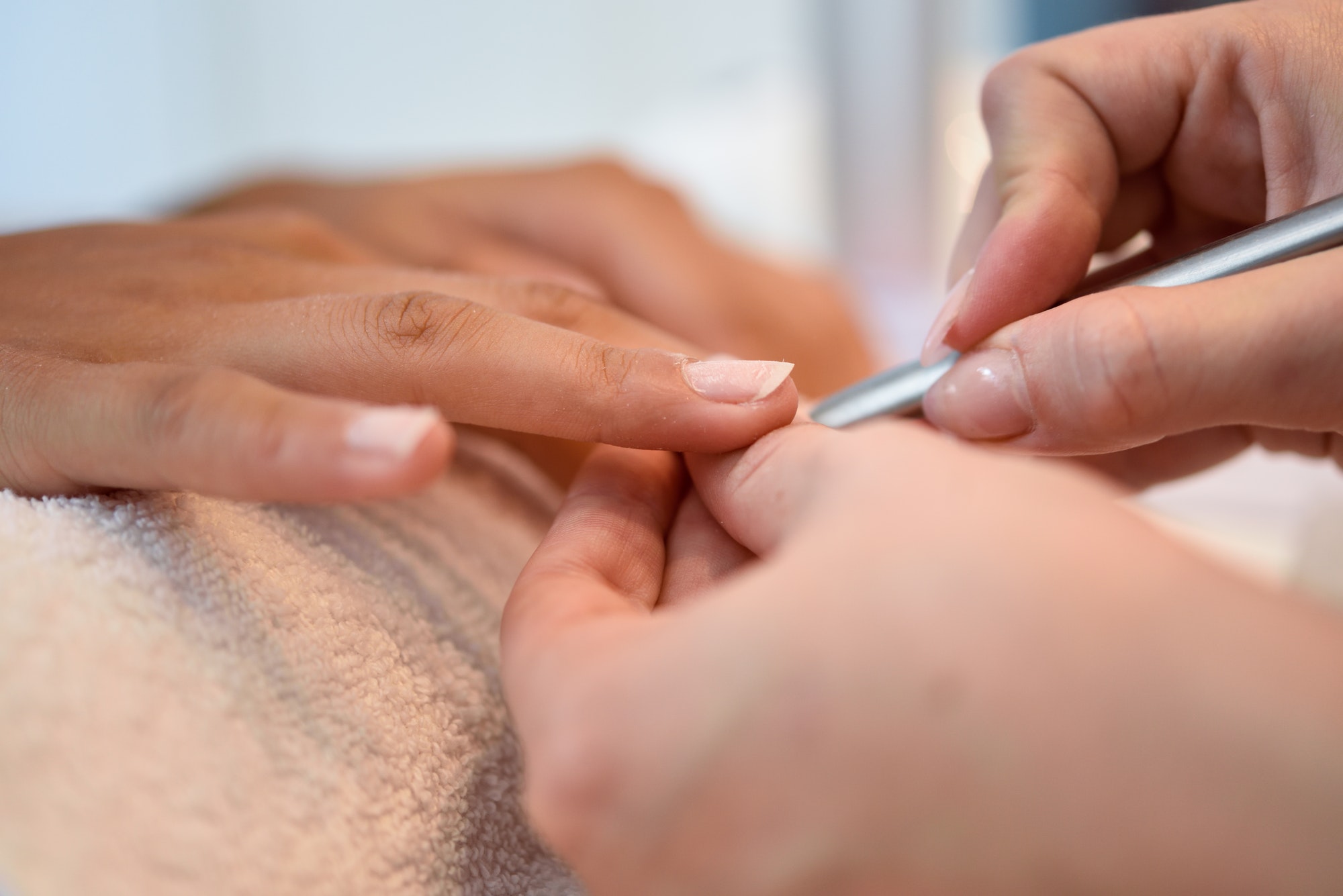 Woman in a nail salon receiving a manicure with nail file