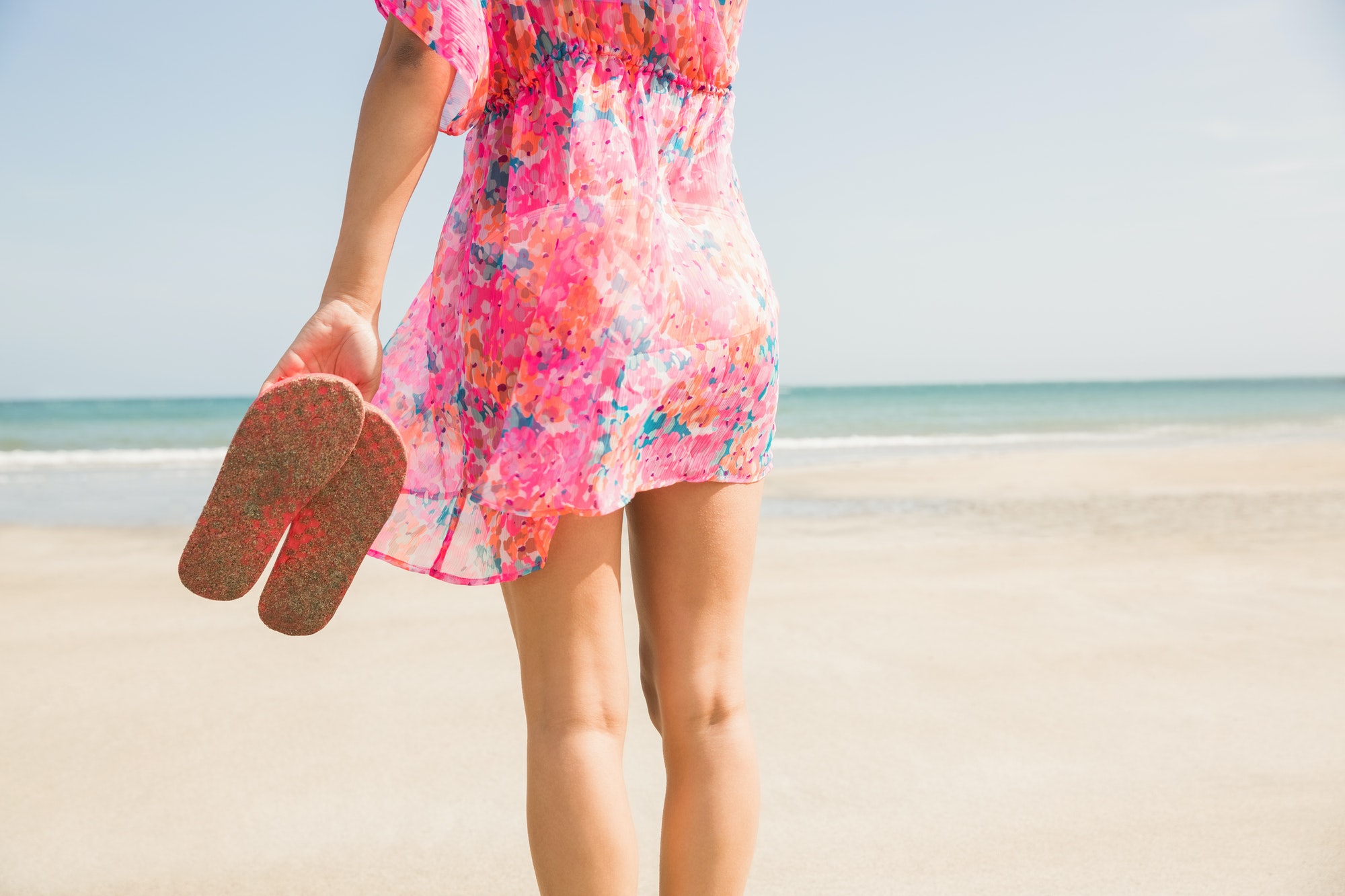 Stylish woman standing on the sand at the beach